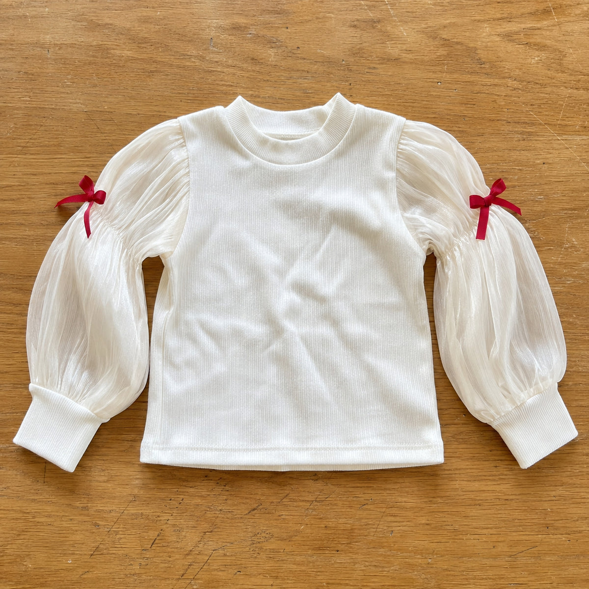 Ivory ribbed top with sheer balloon sleeves and red bows