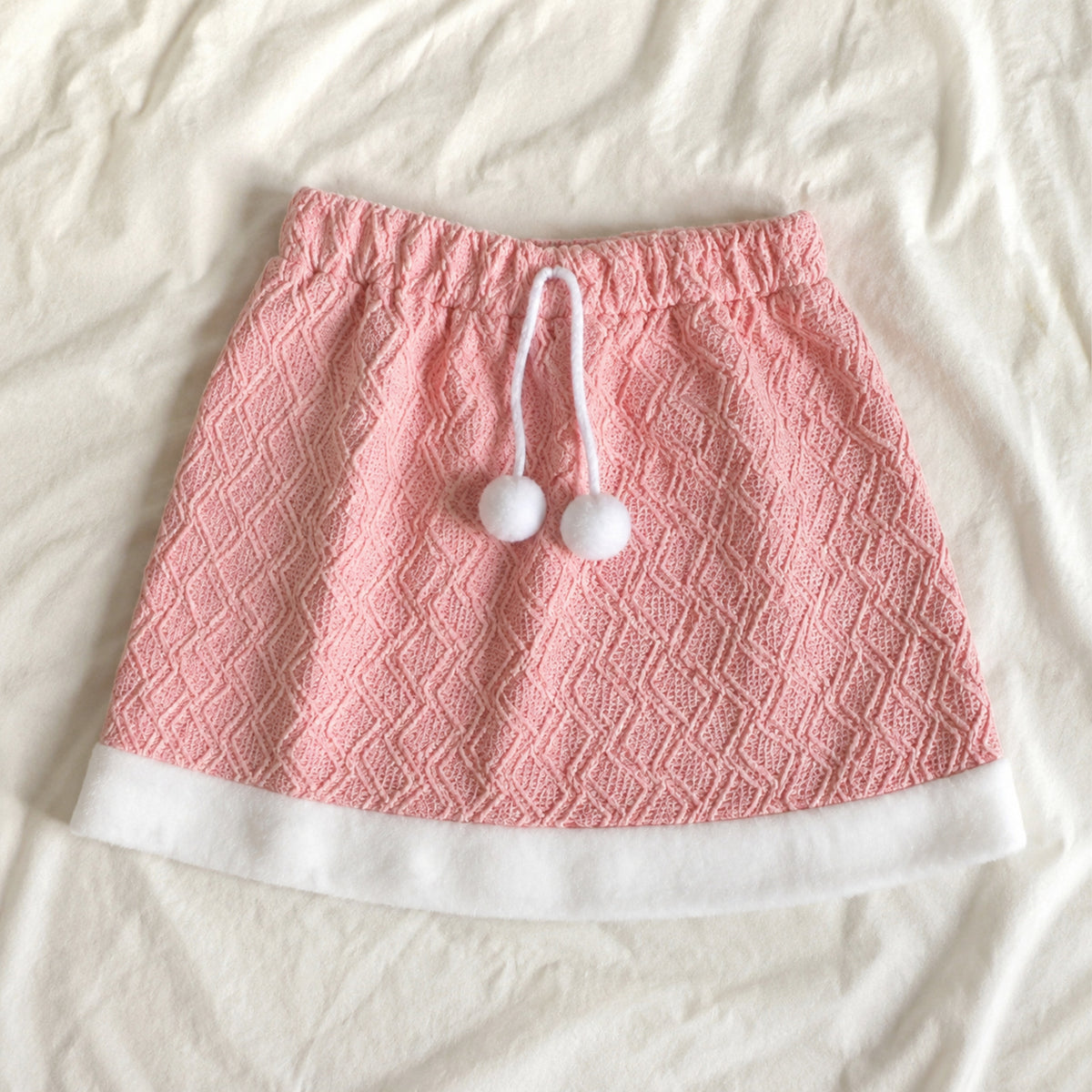 Pink textured skirt with pom poms and ivory hem