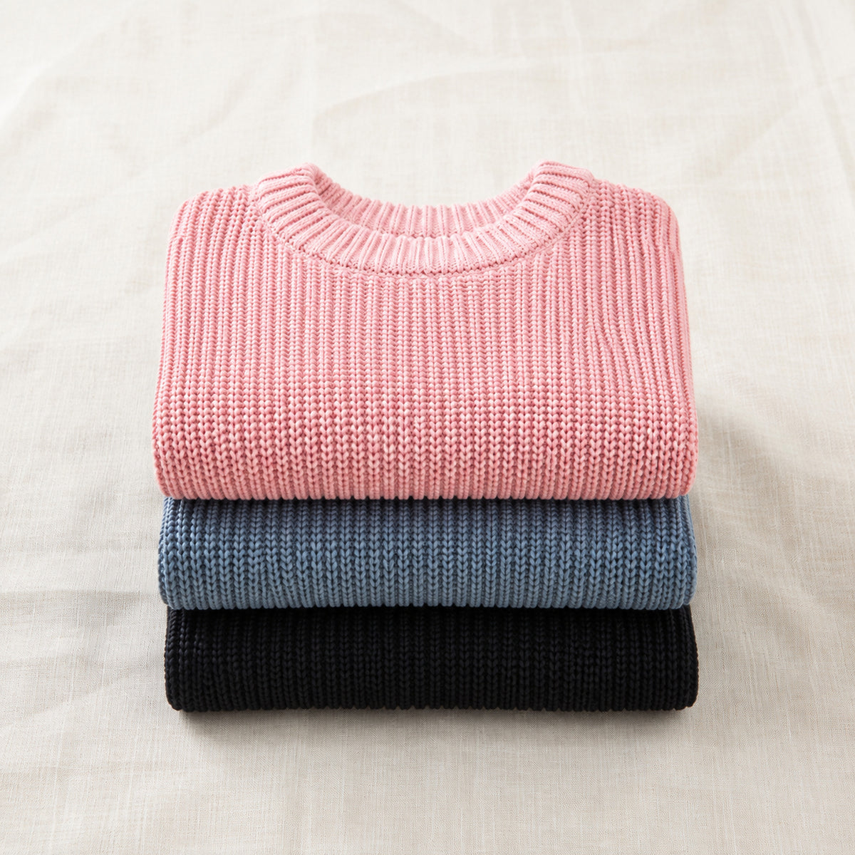 Kids' chunky cotton knit pullovers folded in black blue gray and pink