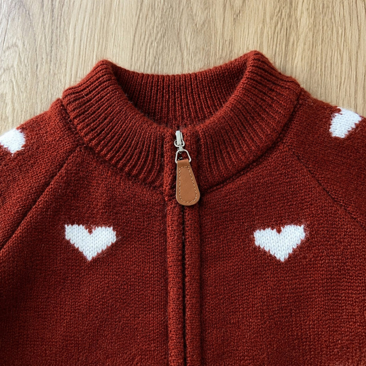 Close-up of red knit cardigan ribbed collar zipper and leather-look pull