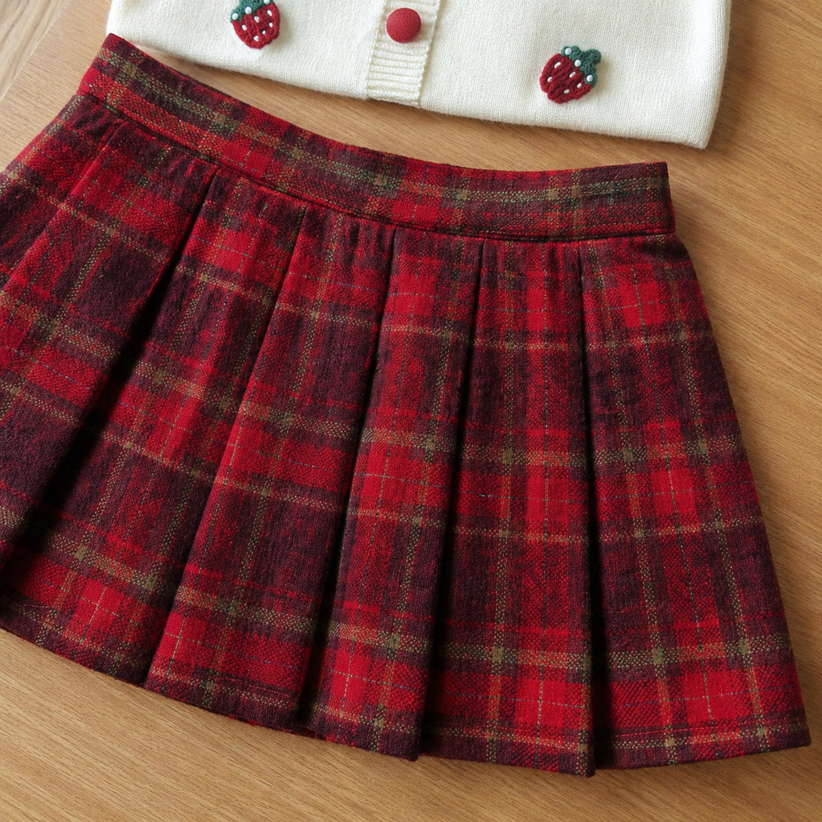 Close-up of the red tartan skirt waistband, pleats and woven texture