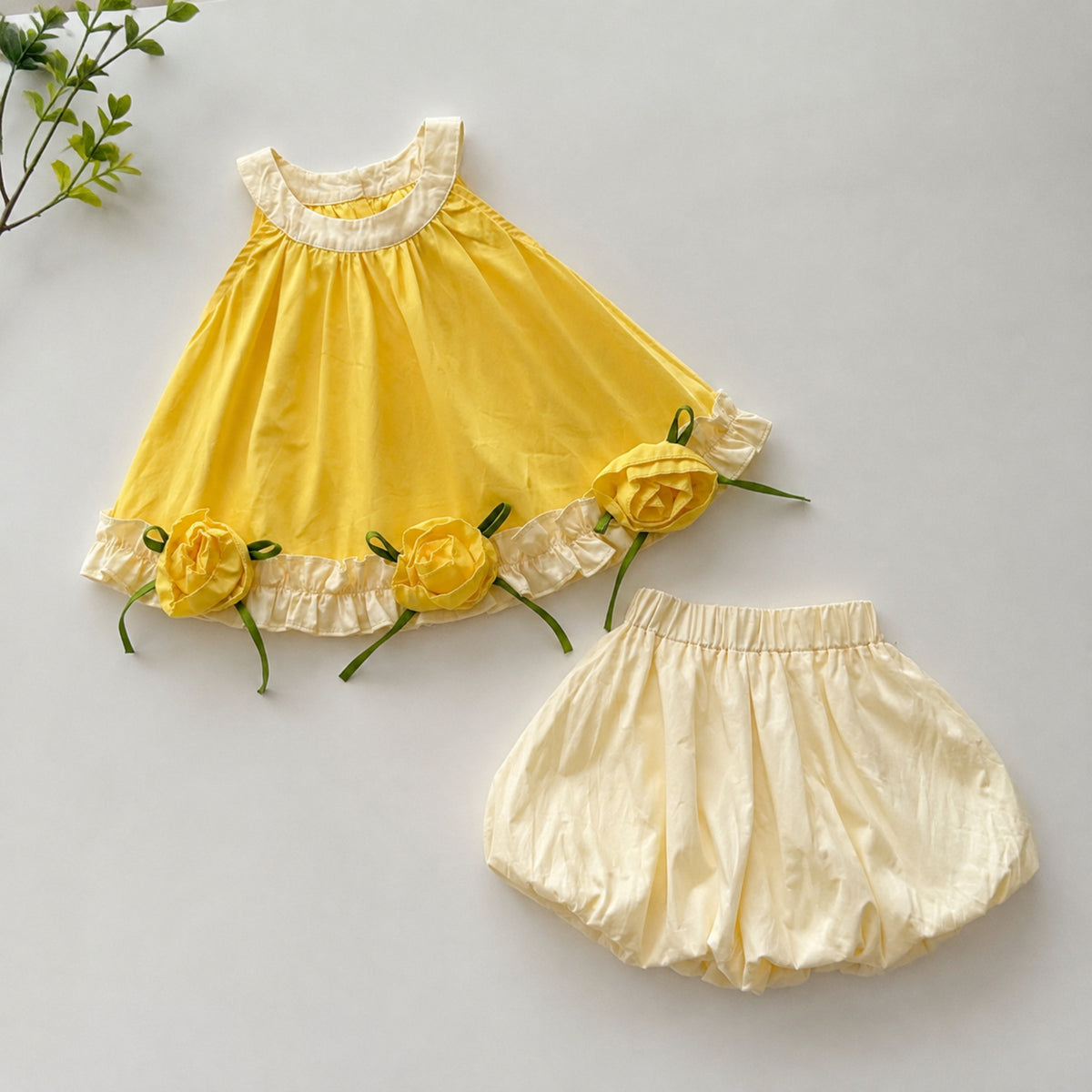 Sunflower rose dress and cream bubble shorts displayed separately on a home table